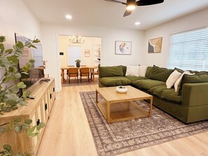 A living room with a green sofa, a wooden coffee table, and a dining area with a table and chairs. - The Hanging Moss Retreat (Jackson)