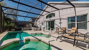 A swimming pool with a glass enclosure, lounge chairs, and a covered patio area. - Villa With Private Pool in Lake Berkley Resort (Kissimmee)