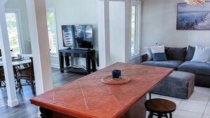 A modern kitchen with a central island, bar stools, and a dining area with a table and chairs. - NEW! Lake Front House,Private Dock,Kayaks,Beach (Troutman)