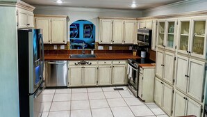 A kitchen with light-colored cabinets, a stainless steel refrigerator, a microwave, and a sink. - NEW! Lake Front House,Private Dock,Kayaks,Beach (Troutman)