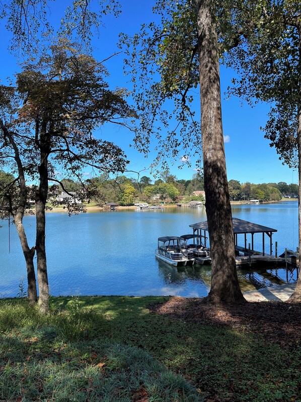 A lake with a dock and boats, surrounded by trees and houses in the background. - NEW! Lake Front House,Private Dock,Kayaks,Beach (Troutman)