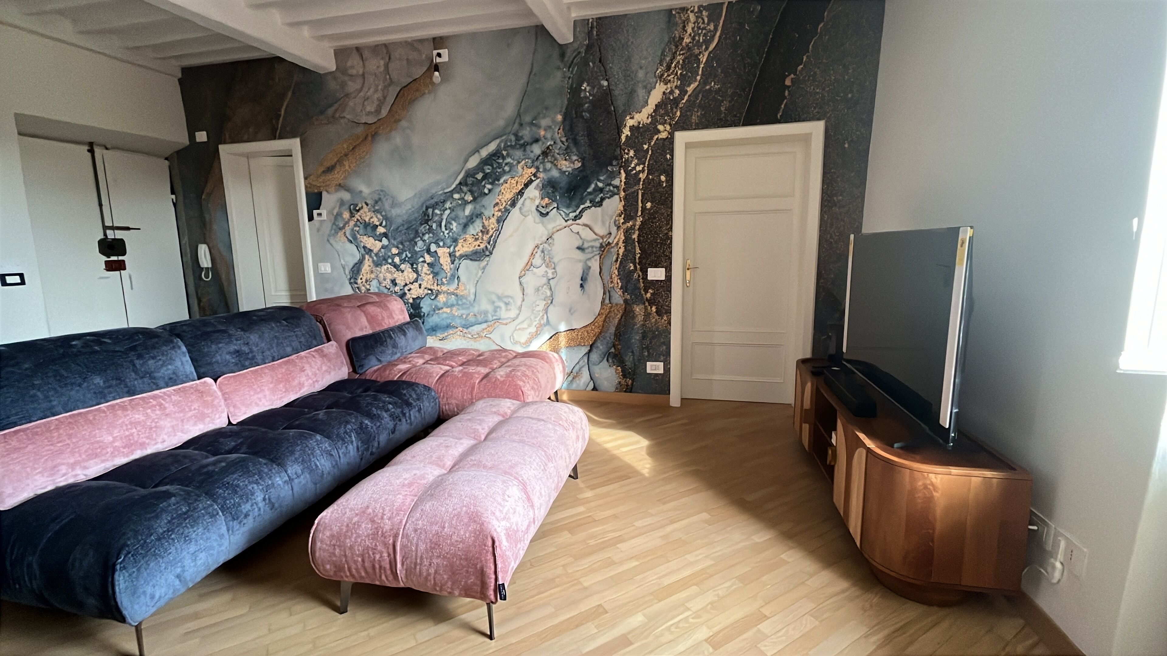 Ein modernes Wohnzimmer mit einer Eckcouch, einem Flachbildfernseher und einer Marmorwand.