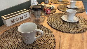 Une table à manger avec du matériel pour préparer le café, un paquet de café et une pancarte indiquant « MAISON ».