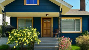 A two-story house with a front porch, a wooden door, and a window with shutters.