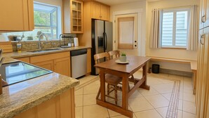 A kitchen with wooden cabinets, a refrigerator, a dishwasher, a granite countertop, and a dining table with chairs. - The Burke House Collection by Stay Rested  (Seattle)