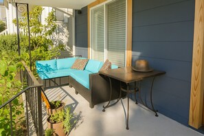 A balcony with a blue sofa, a small table, and potted plants. - The Burke House Collection by Stay Rested  (Seattle)