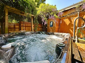 A hot tub with a wooden deck and a wooden fence in the background. - The Burke House Collection by Stay Rested  (Seattle)