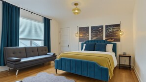 A modern bedroom with a bed, a sofa, and a small table. - The Burke House Collection by Stay Rested  (Seattle)