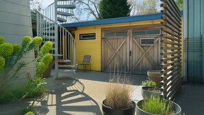 A modern building with a yellow exterior, a wooden fence, and a staircase leading to a garage. - The Burke House Collection by Stay Rested  (Seattle)