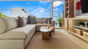 Una sala de estar moderna con un sofá color beige, una mesa de centro de madera y un televisor montado en la pared.