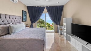 A bedroom with a bed, a TV, and a view of the outdoors.