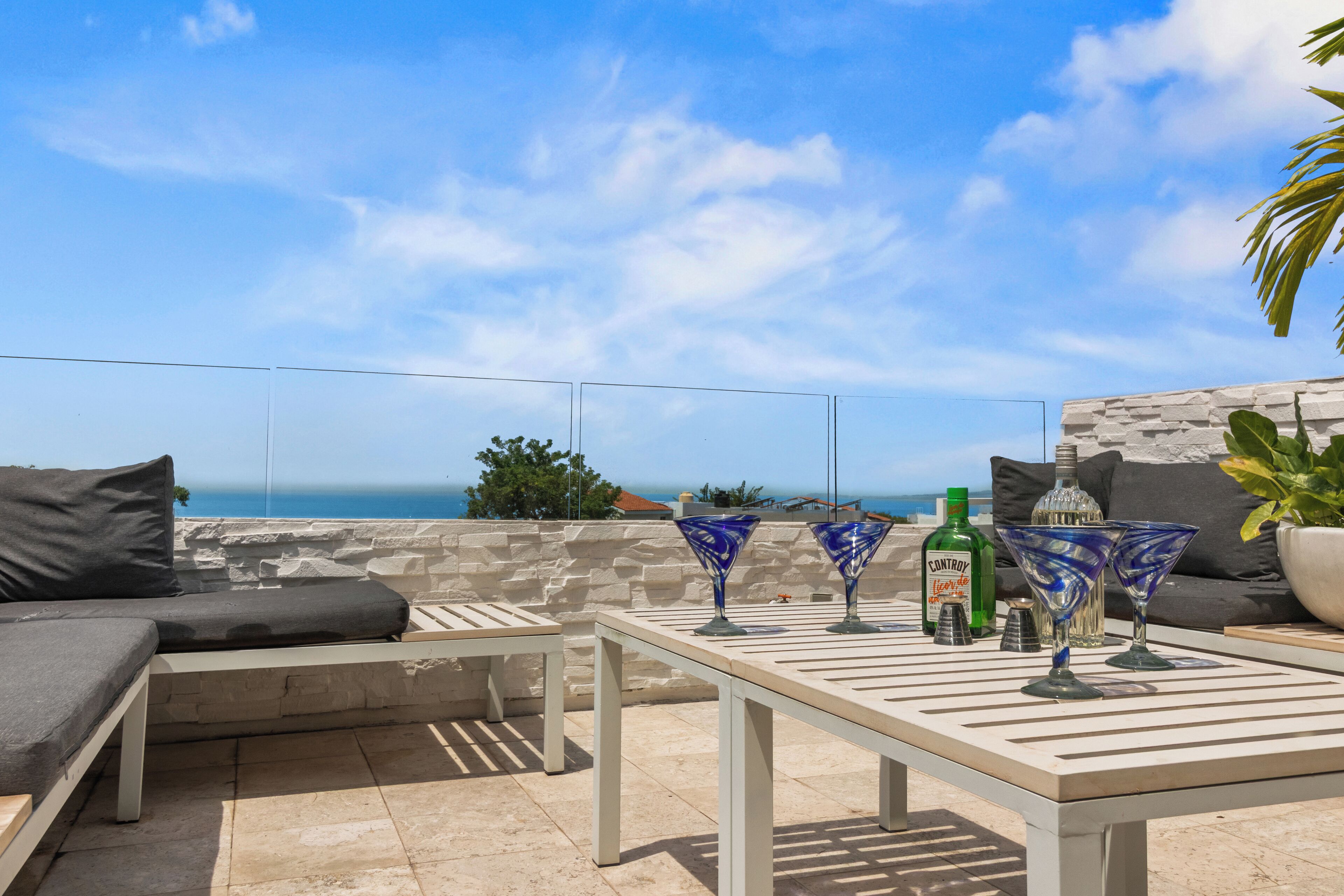 An outdoor seating area with a table, cushions, and decorative glasses.