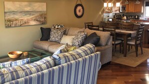 A living room with a sofa, a coffee table, and a painting on the wall. - Beach Block condo, 2 bed, 2.5 bath - Perfect for couples or small families! (Brigantine)