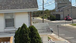 A residential street with houses, a stop sign, and a car parked on the side.