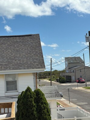 A residential street with houses, a stop sign, and a car parked on the side.