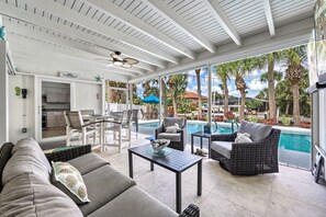 A spacious patio with a pool, outdoor seating, and a kitchen area visible through large windows.