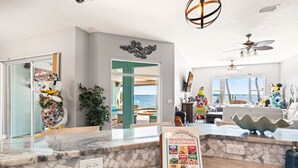 A modern kitchen with a marble countertop, a view of the sea, and a sign for brand-name recipes.