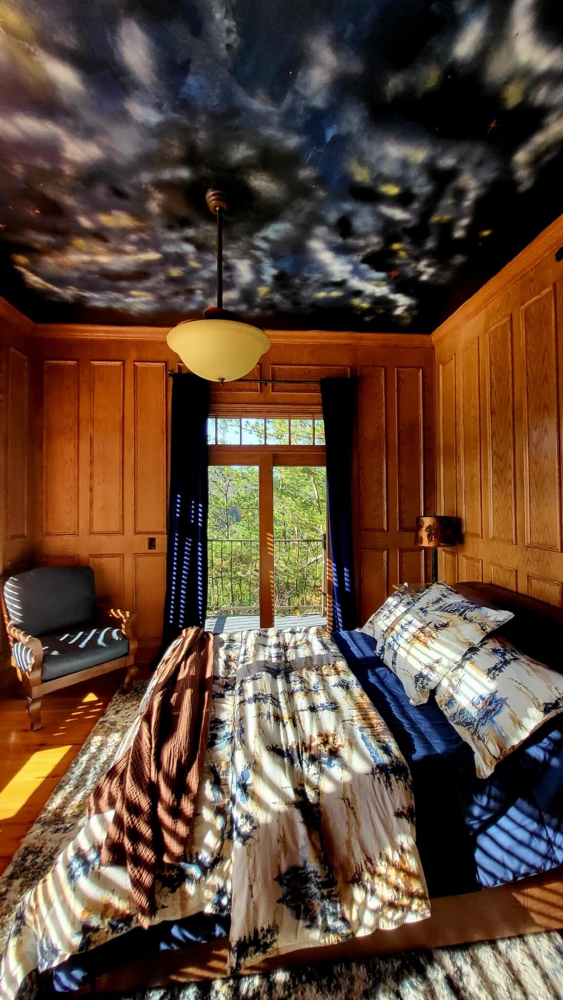A room with a bed, a chair, and a window with curtains.