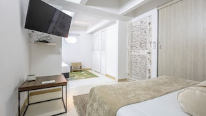 A bedroom with a bed, a TV mounted on the wall, a bedside table, and a wardrobe.