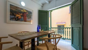 A dining area with a wooden table, wicker chairs, and a framed painting on the wall.