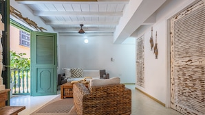 A room with a wicker sofa, a wooden bench, a green door, and a white ceiling.