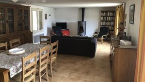 A living room with a fireplace, a dining area with a table and chairs, and a bookshelf. - La Téolière (countryside and private pool) (FIGANIERES)