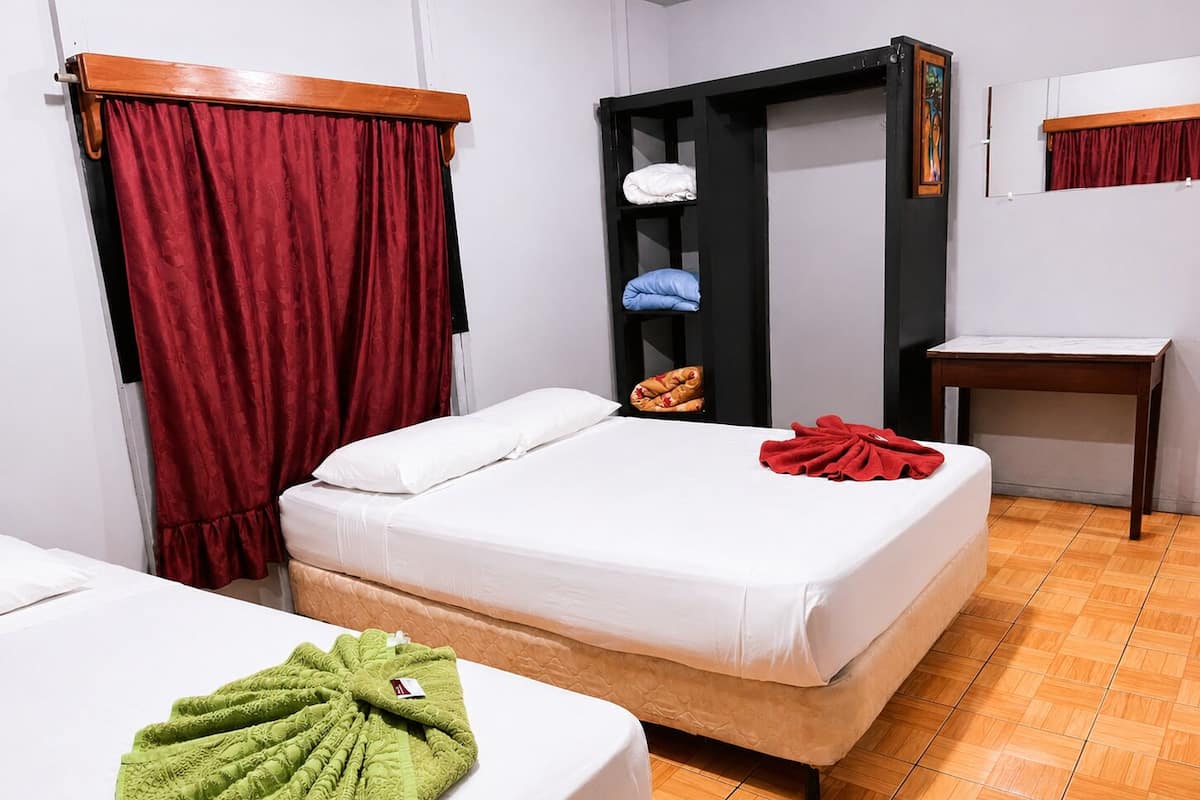 A hotel room with a bed, a wardrobe, a small table, and a mirror.