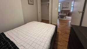 Une chambre à coucher avec un lit, une commode et une porte ouverte donnant sur un couloir.