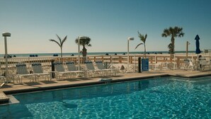 Un espace piscine équipé de chaises longues et d’un panneau indiquant qu’il est interdit de plonger.