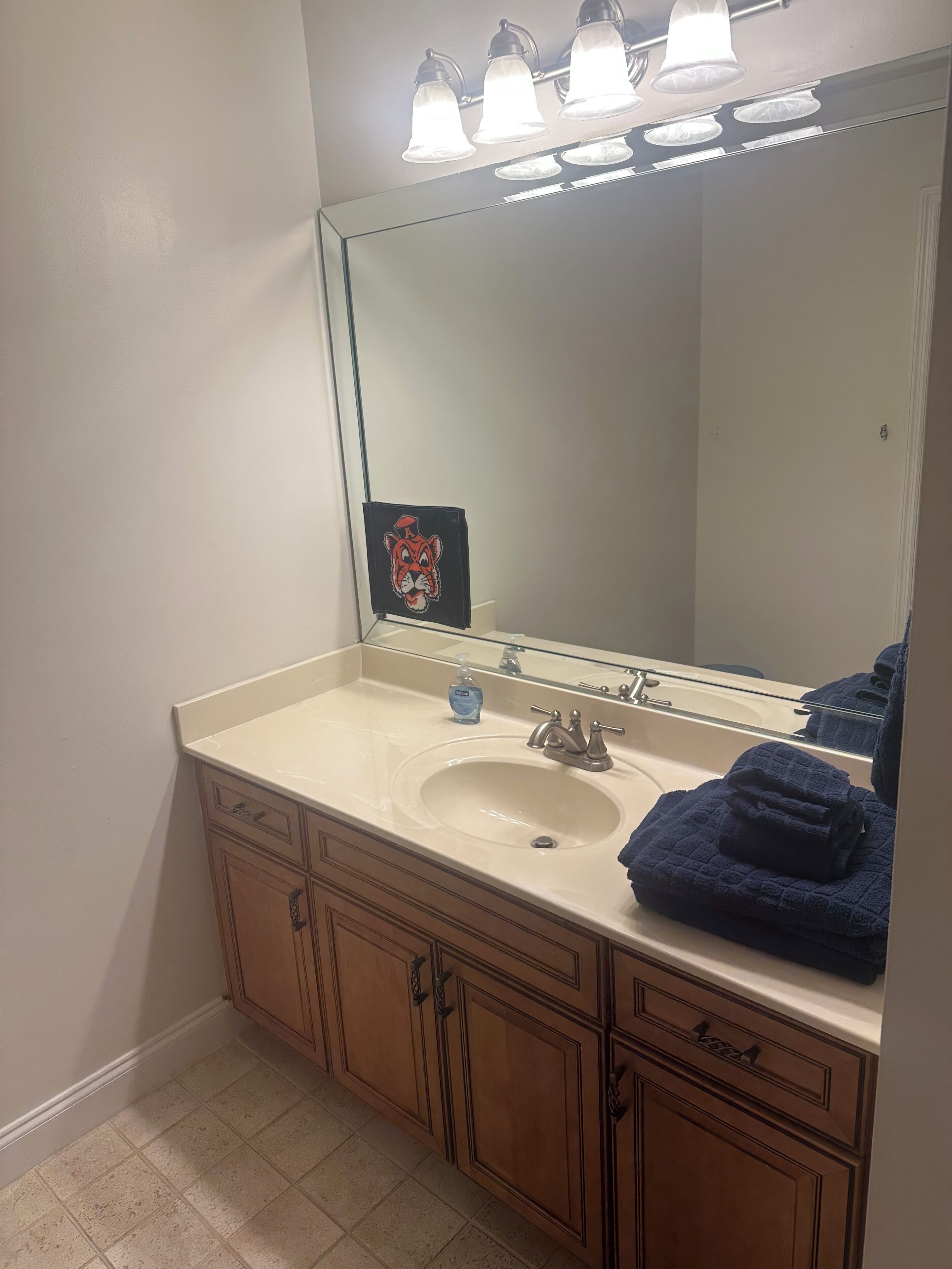 Un baño con lavamanos, espejo y armarios.