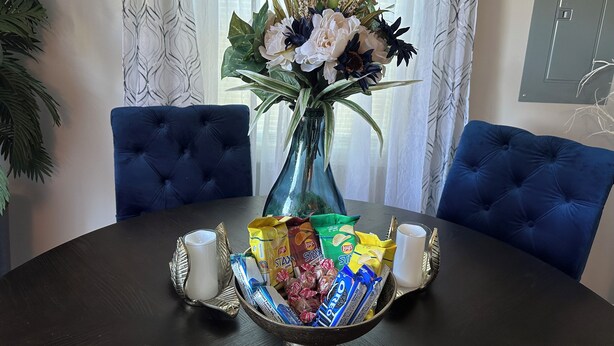 A dining table with a vase of flowers, two blue cushioned chairs, and a tray with snacks and drinks. - Charming family friendly 3-bedroom house in  Painter with AC and outdoor patio (Painter)
