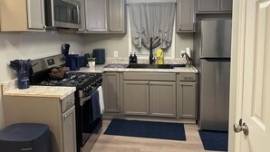 A compact kitchen with a microwave, stove, sink, and refrigerator. - Charming family friendly 3-bedroom house in  Painter with AC and outdoor patio (Painter)