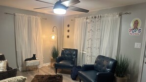 A living room with two black leather sofas, a fluffy brown rug, a ceiling fan, and a wall-mounted light fixture. - Charming family friendly 3-bedroom house in  Painter with AC and outdoor patio (Painter)
