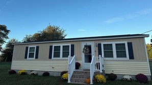 A single-story mobile home with a front porch, a small staircase, and a mailbox. - Charming family friendly 3-bedroom house in  Painter with AC and outdoor patio (Painter)