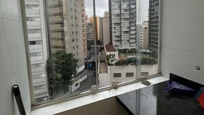 A view from a balcony with a large window overlooking a cityscape. - Apto próx à Paulista e metro Trianon (São Paulo)