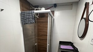 A bathroom with a toilet, a shower enclosure, a sink, and a mirror. - Apto próx à Paulista e metro Trianon (São Paulo)