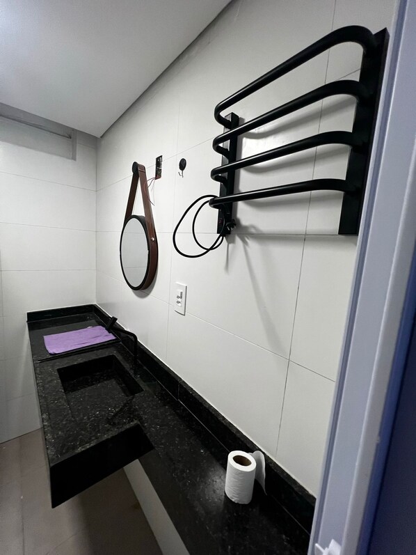 Une salle de bain avec deux lavabos, un porte-serviettes et un distributeur de papier toilette.