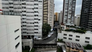 A high-rise urban area with multiple buildings, including a prominent white building with numerous windows and balconies. - Apto próx à Paulista e metro Trianon (São Paulo)