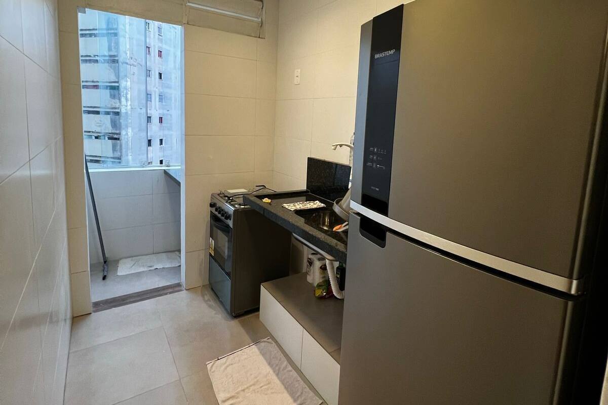 Cocina compacta con refrigerador de acero inoxidable, horno empotrado y una pequeña encimera con estufa.
