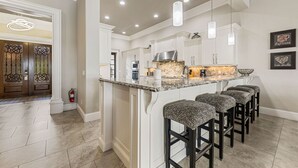 A spacious kitchen with a large island, pendant lighting, and a fire extinguisher.