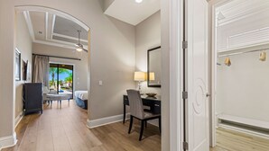 A hotel room with a bed, a desk with a chair, a lamp, and a large mirror.