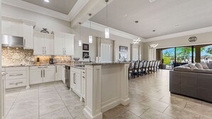 A modern kitchen with white cabinetry, granite countertops, and a central island.