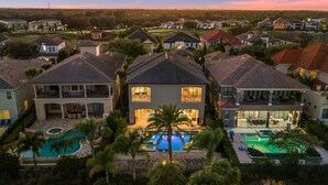 A residential area with multiple houses, a central swimming pool, and a golf course in the background.