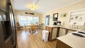 A kitchen with wooden cabinets, a refrigerator, a dining table with chairs, and a window with blinds. - Waterfront! Prime Location, Clean, Swimming Pool, Fishing Dock, WIFI (George town)