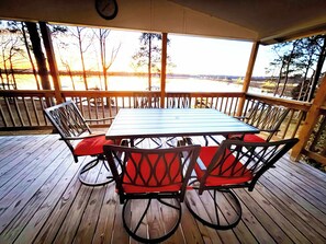A covered outdoor patio with a wooden table and chairs, a clock on the wall, and a view of trees and a body of water. - Waterfront! Prime Location, Clean, Swimming Pool, Fishing Dock, WIFI (George town)
