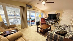 A living room with a sofa, a coffee table, a television, and a bicycle. - Waterfront! Prime Location, Clean, Swimming Pool, Fishing Dock, WIFI (George town)