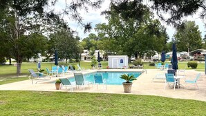 A pool area with lounge chairs, a small shed, and a flagpole. - Waterfront! Prime Location, Clean, Swimming Pool, Fishing Dock, WIFI (George town)
