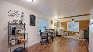 Un espace repas avec une table et des chaises en bois, un coin café et un tableau présentant le menu.