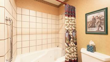Un baño con bañera, cortina de ducha estampada y un cuadro en la pared.