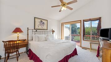 A bedroom with a bed, desk, chair, TV, and a ceiling fan.